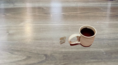 © S.L.Reay photograph of a cup of coffee and several coins on a wood-like counter